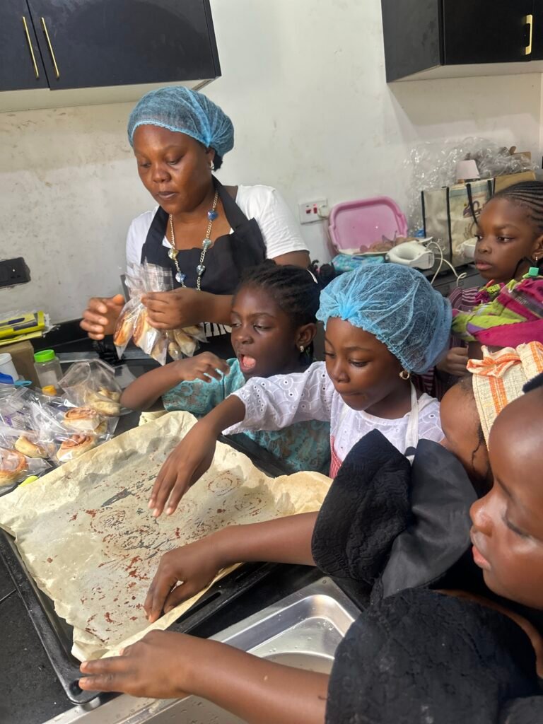 Pupils in hair nets preparing food with a member of staff during a cooking activity