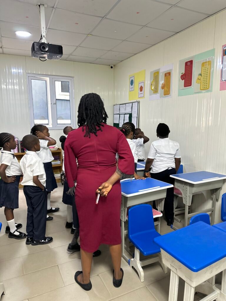 A teacher with pupils in a classroom with blue desks and wall displays