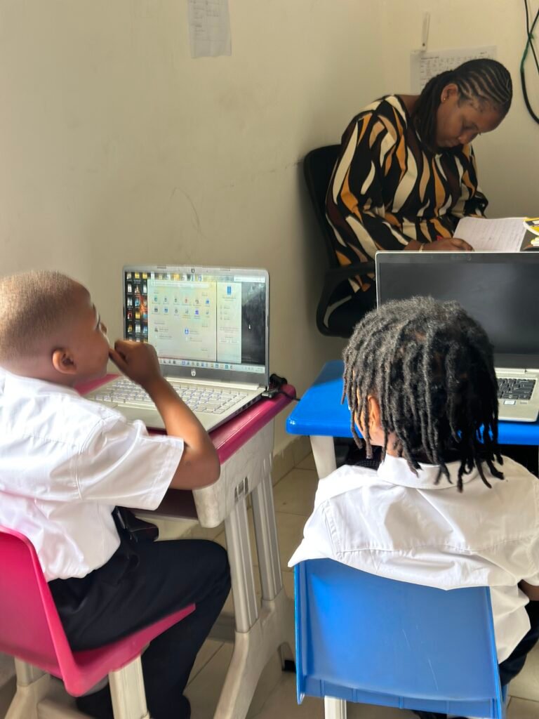 Pupils using a laptop during a computer lesson, with their teacher nearby